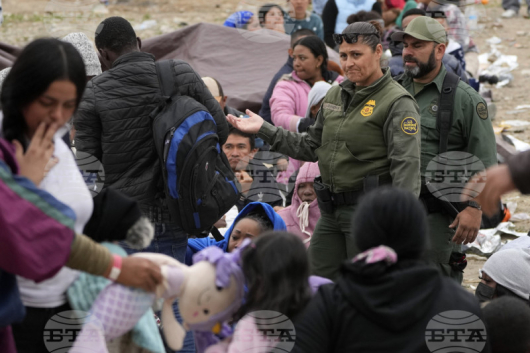 Служители на американската гранична служба преминават през множеството от мигранти, струпани на границата между Мескико и САЩ в Сан Диего, щата Калифорния. Снимка: АП.