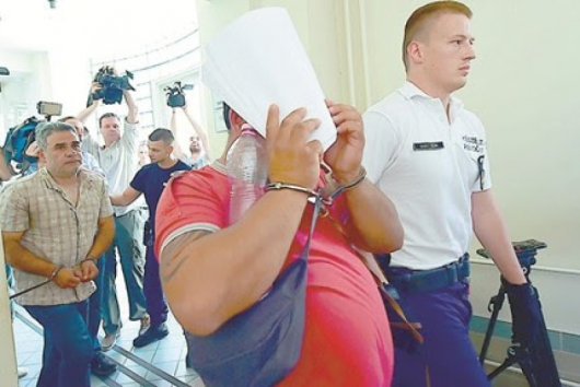 Единият от задържаните трафиканти на мигранти криеше лицето си от журналистите в Кечкемет. Снимка АФП