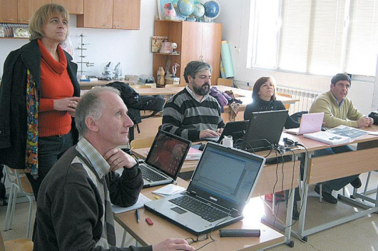 Преподавателката Даниела Йовкова /вляво/ следи на екран на стената данните, които въвеждат в интернет колегите й чужденци по време на обучението им