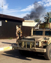 Части на иракската армия преминават пред сграда с изрисуван флаг на ”Ислямска държава”. Сн.: EPA/БГНЕС