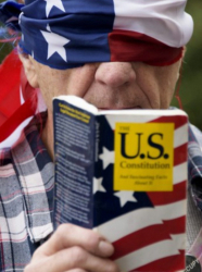Покрил очите си с американското знаме, нюйоркчанин протестира срещу Доналд Тръмп, правейки се, че чете конституцията на САЩ. Сн.: EPA/БГНЕС